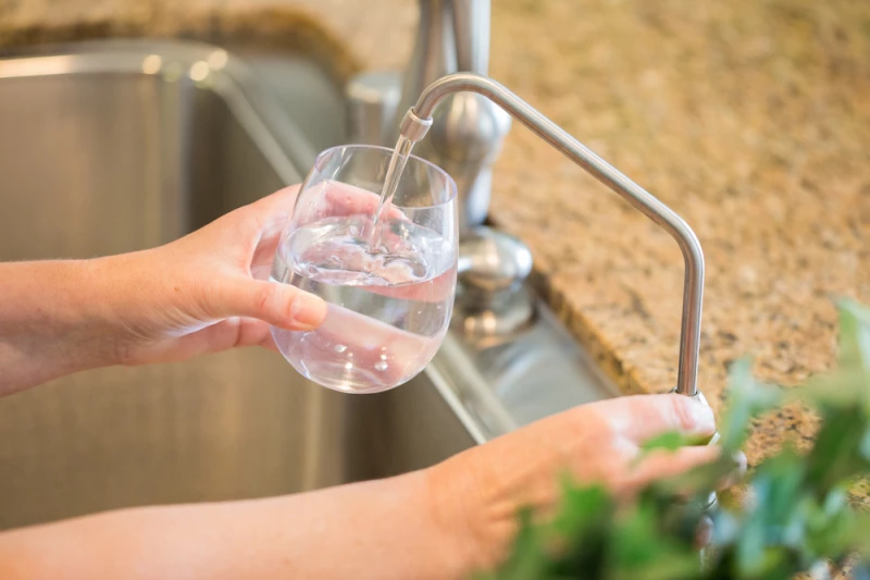 Person pouring water into glass from water filter